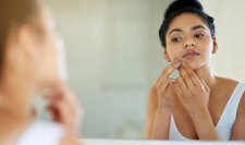 Woman with acne-prone skin looking in a mirror Woman with acne-prone skin looking in a mirror
